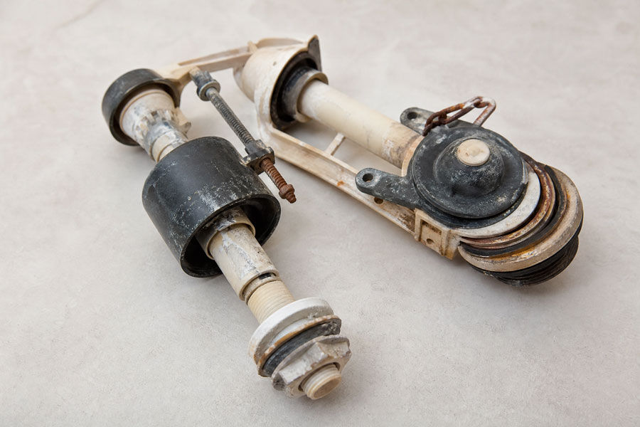 Vintage toilet valve assembly with ceramic and metal components, including rubber seals and adjustment mechanisms