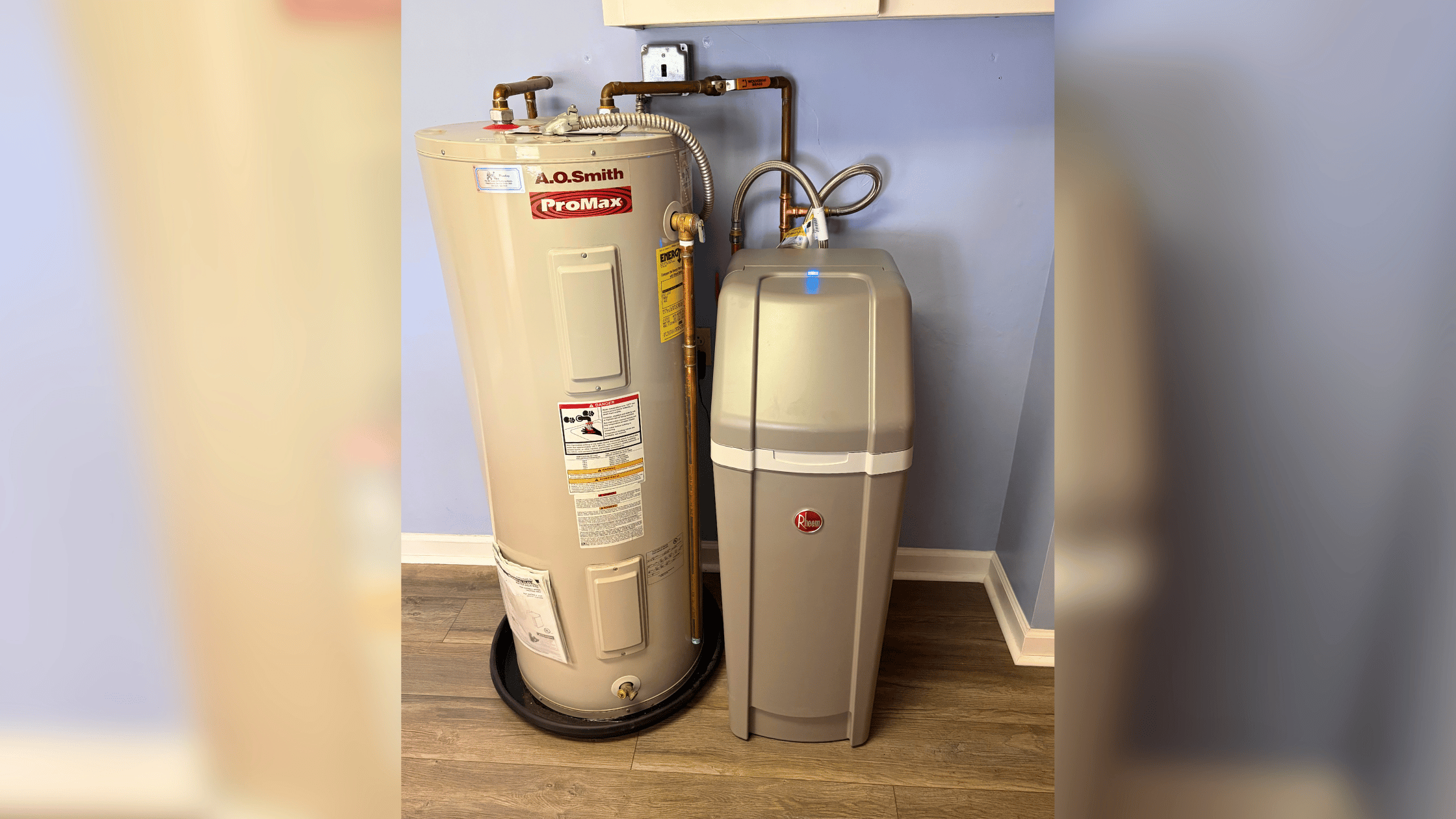 A.O. Smith ProMax water heater tank connected to a water softener system in a basement utility room