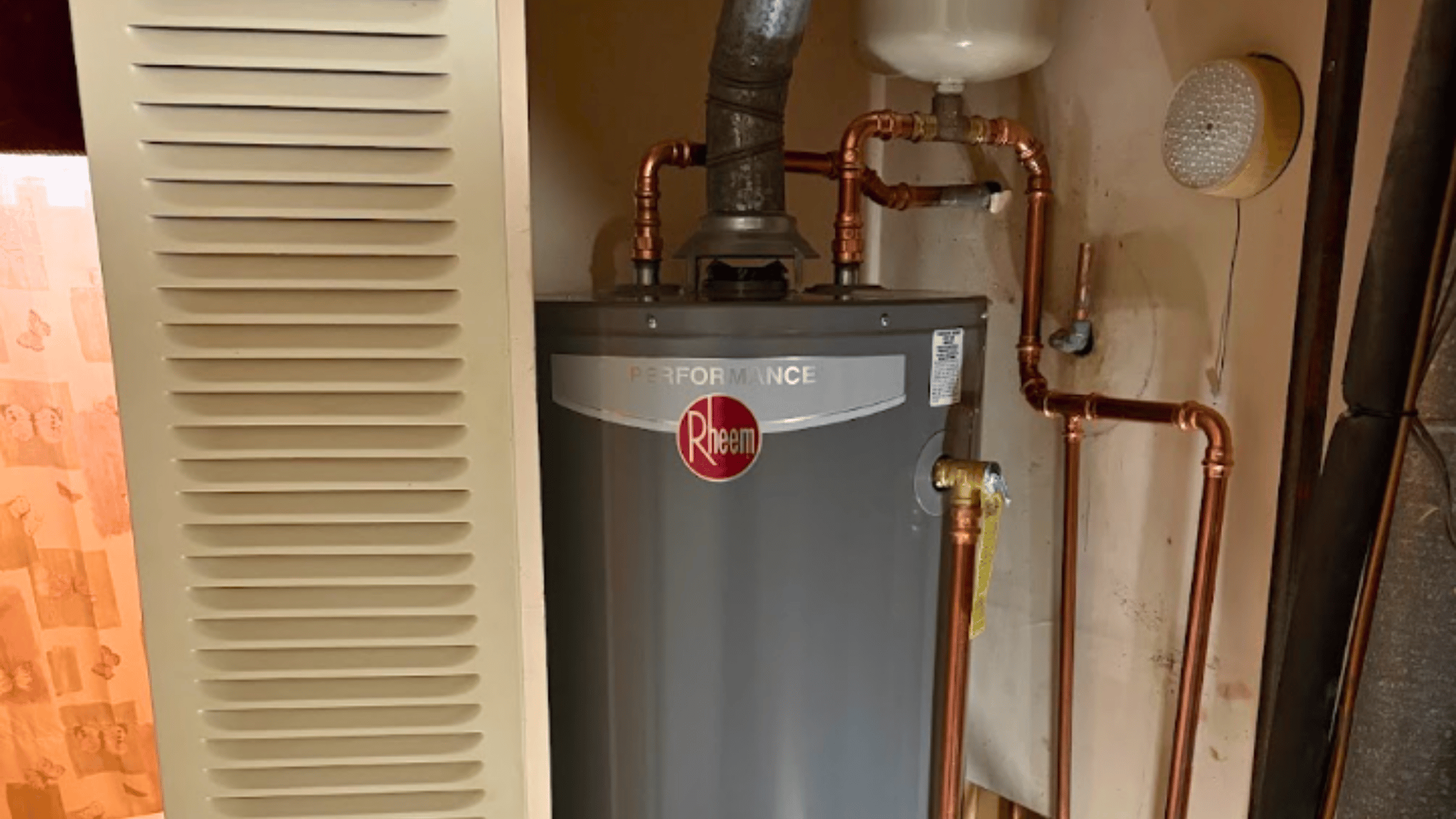 Rheem Performance tank water heater with copper piping and brass connections in a home utility room